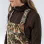 First Lite Women’s Phase Bib in Specter camo with windproof fleece softshell, magnetic cargo pockets, and full-length side zips
